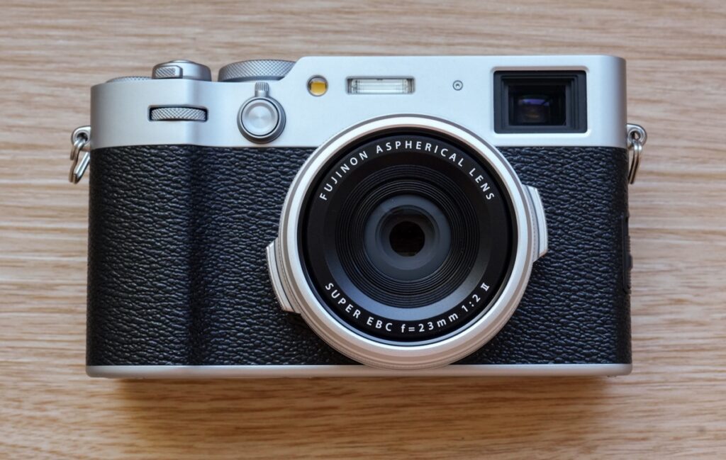Appareil photo Fujifilm X100VI posé sur une table en bois, compact expert avec objectif fixe 23 mm f/2, idéal pour la street photography et les voyages.