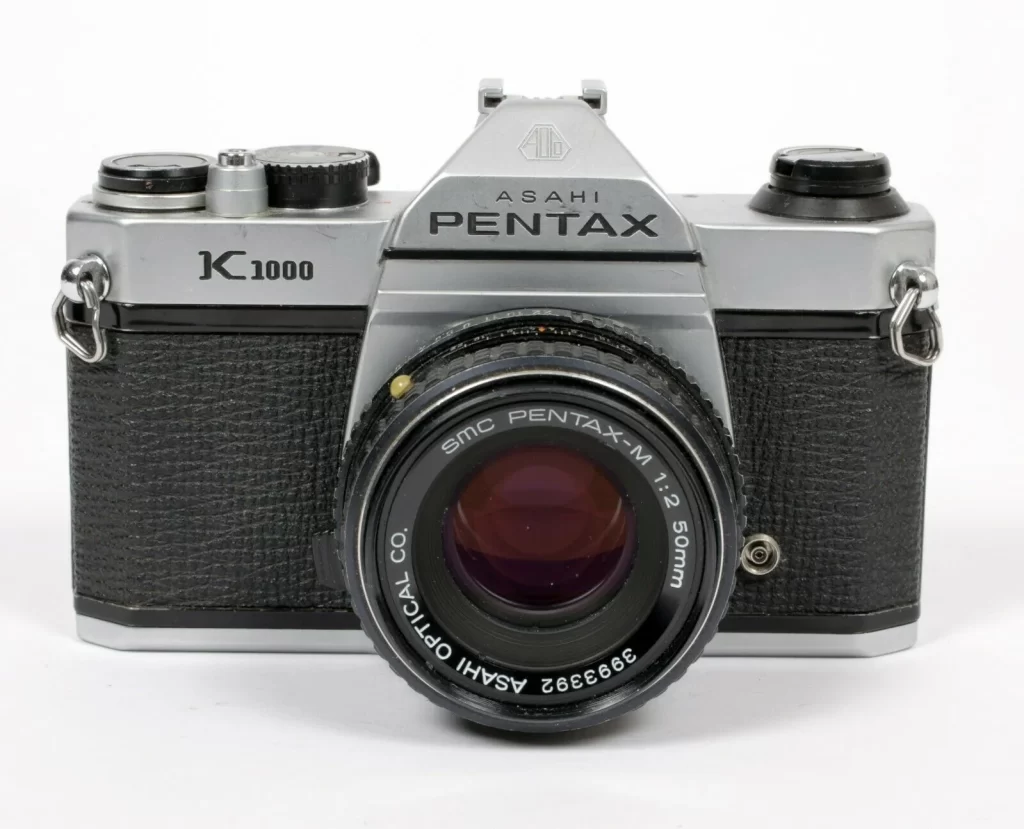 Pentax K1000 utilisé par un étudiant en photographie, ambiance atelier d’école d’art.