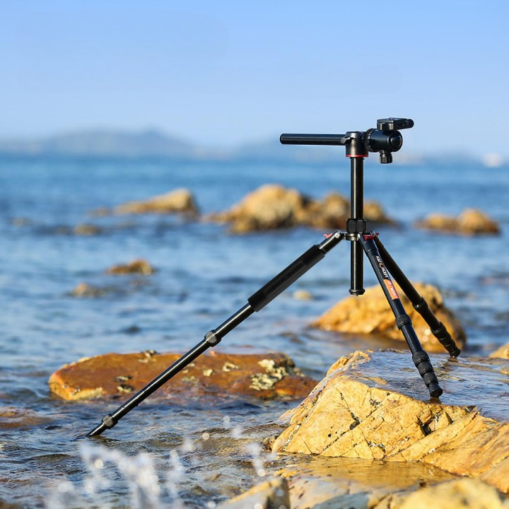 Trépied en fibre de carbone utilisé dans l'eau salée sur une plage pour illustrer sa résistance naturelle à la corrosion.