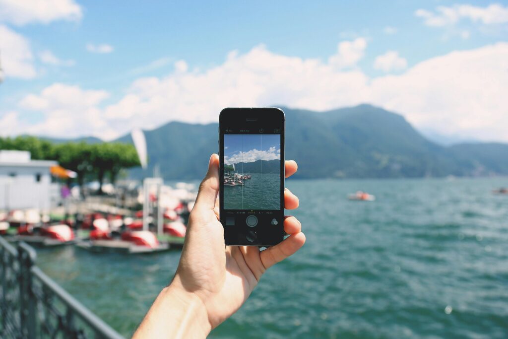 Main tenant un smartphone face à l’horizon, illustrant la liberté et la créativité de la photographie mobile.