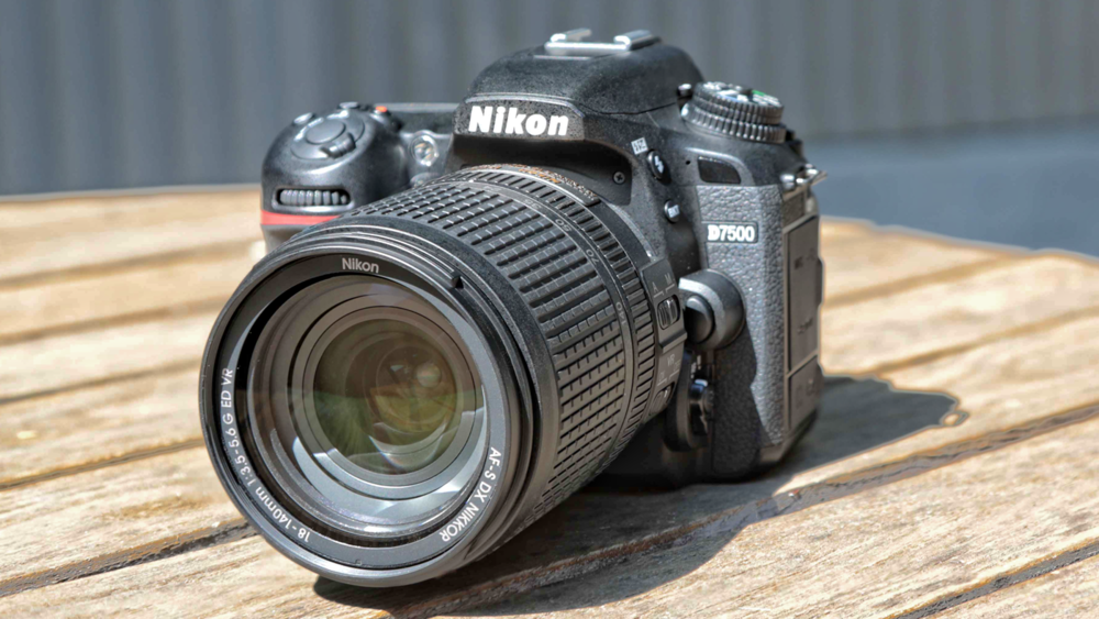 Photographe tenant un appareil photo reflex Nikon D7500 prêt à capturer un paysage au lever du soleil
